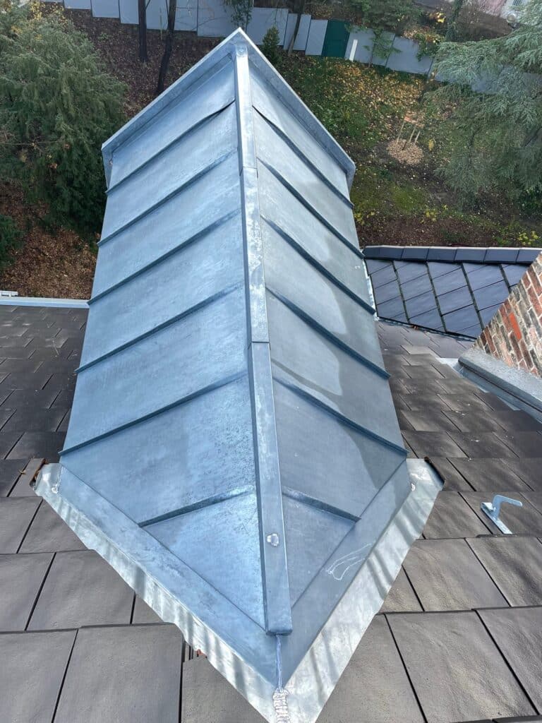 Toiture en Zinc à Joint Debout : Travaux de Zinguerie Toiture en zinc à joint debout installée sur un toit en ardoises sombres, vue de dessus précise et technique.